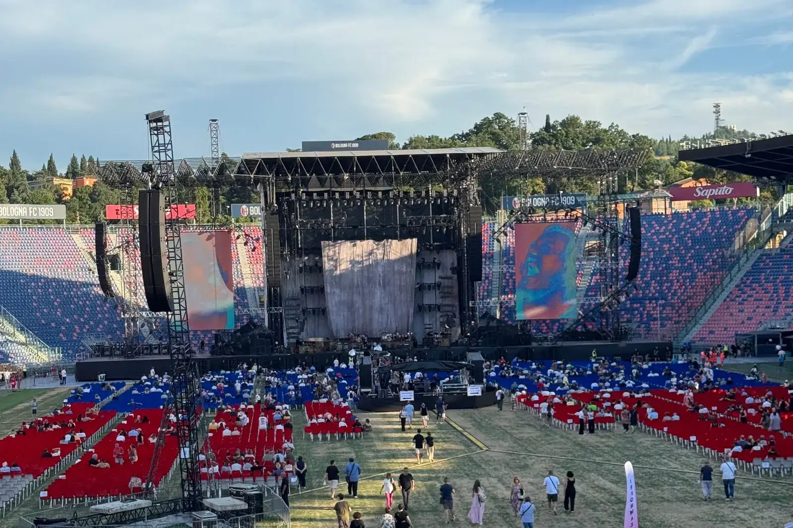 Palco all'aperto con il parterre allestito e il pubblico che entra prima del concerto