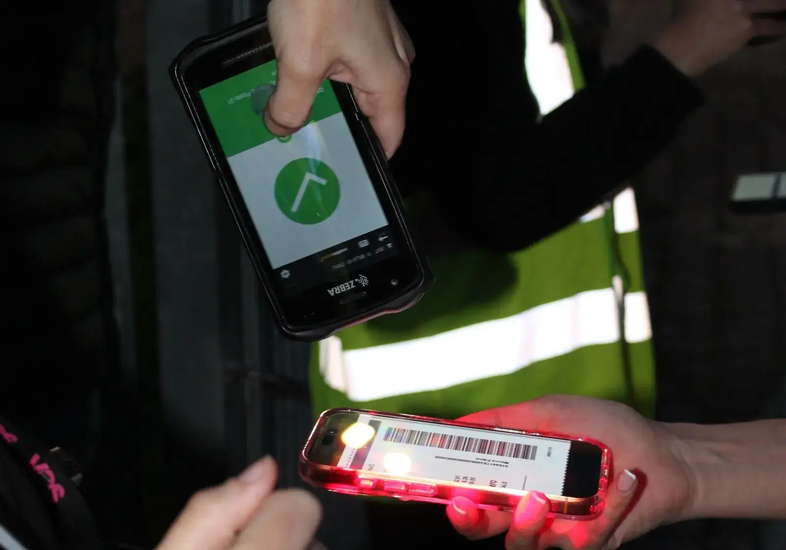 Operatrice YES in gilet scansiona il biglietto di uno spettatore al buio, con il lettore che conferma l'ingresso