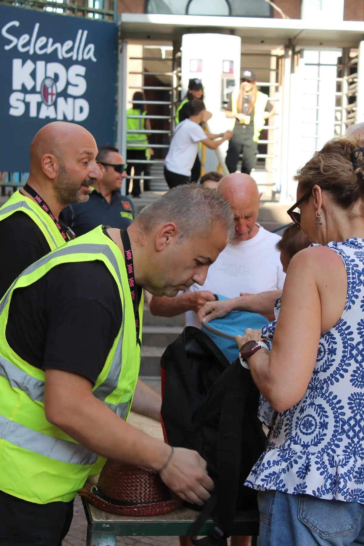 Uno steward YES controlla lo zaino di una spettatrice al varco d'ingresso, con la squadra alle spalle