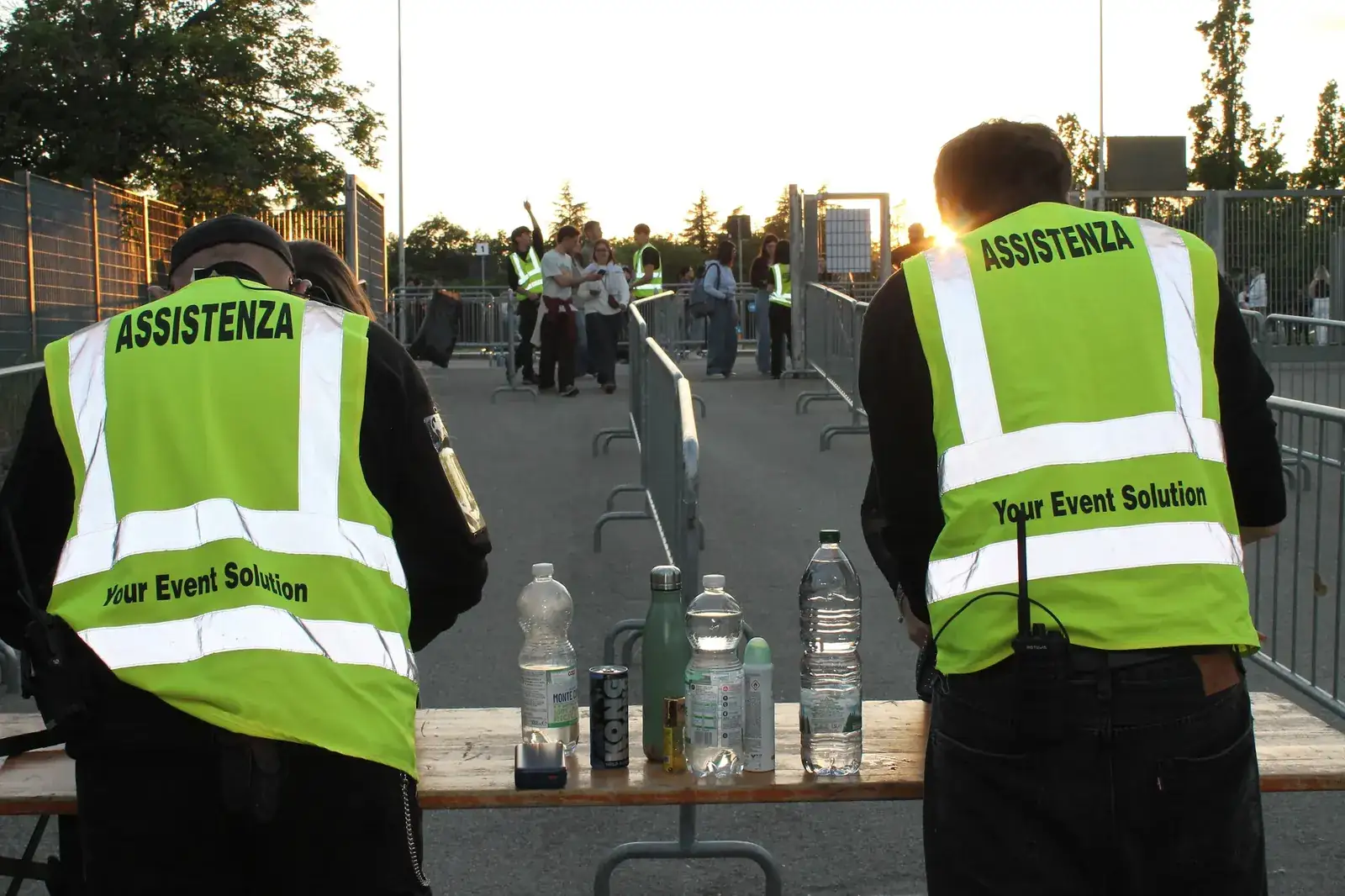 Due steward YES con la pettorina Assistenza presidiano i varchi d'ingresso di uno stadio al tramonto