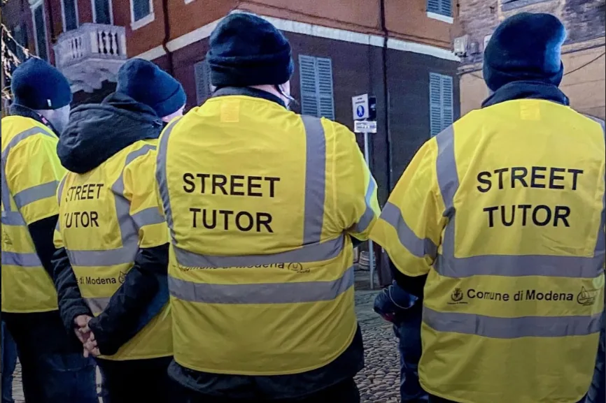 Street tutor YES con la pettorina gialla del Comune di Modena, di spalle, in servizio in centro città